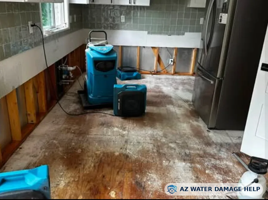 Kitchen with flood-cut drywall, removed flooring and a dehumidifier running